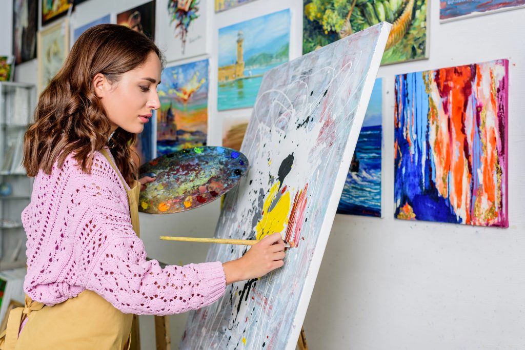 side view of beautiful female artist painting in workshop