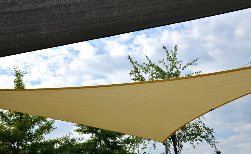 white canvas stretched, shading from sun and rain over terrace ofrestaurant, on playground in kindergarten, on platform of the promenade. pergola with metallic gray beams , cable, electric, bulb, led