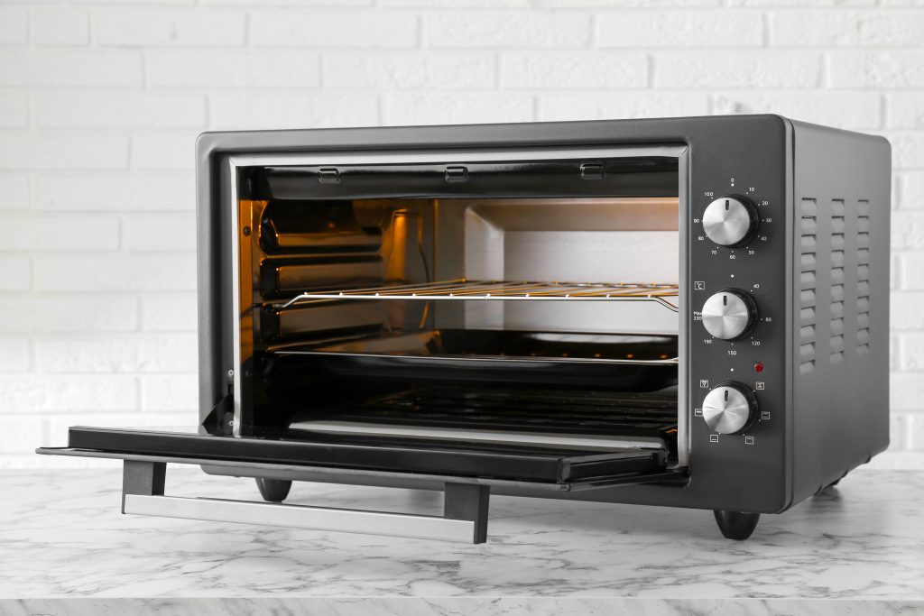 One electric oven on white marble table near brick wall