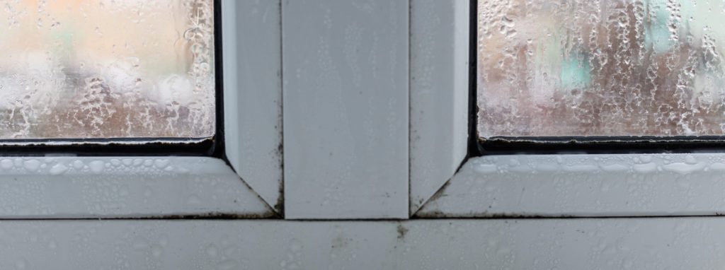Glass of window with condensation, natural water drops on glass, high humidity. Selective focus.